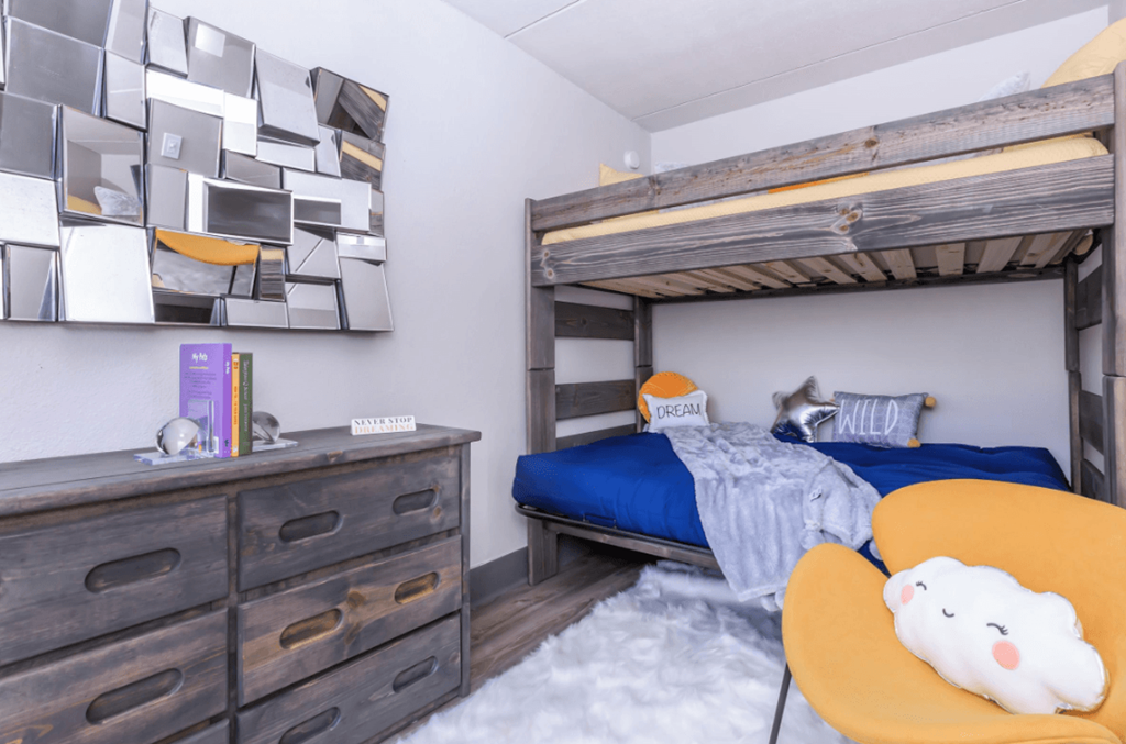 A room with a bunk bed, a dresser, and a wall art.