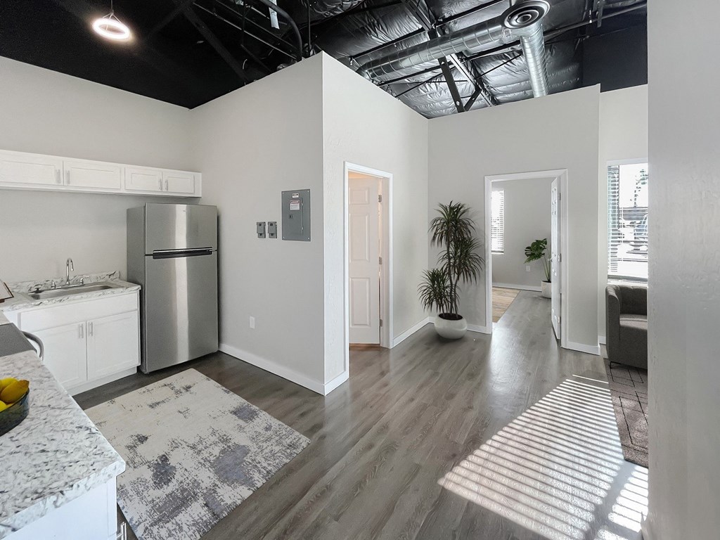 A kitchen with a refrigerator, sink, and a dining table with chairs.