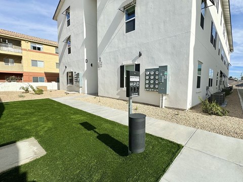 A white building with a grey trash can in front of it.