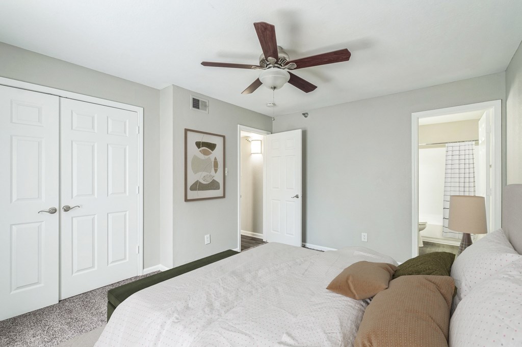 A bedroom with a white bed and a ceiling fan.