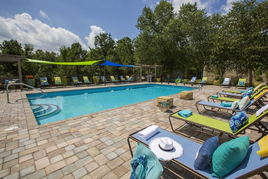 A pool area with a table and chairs and a hat on it.