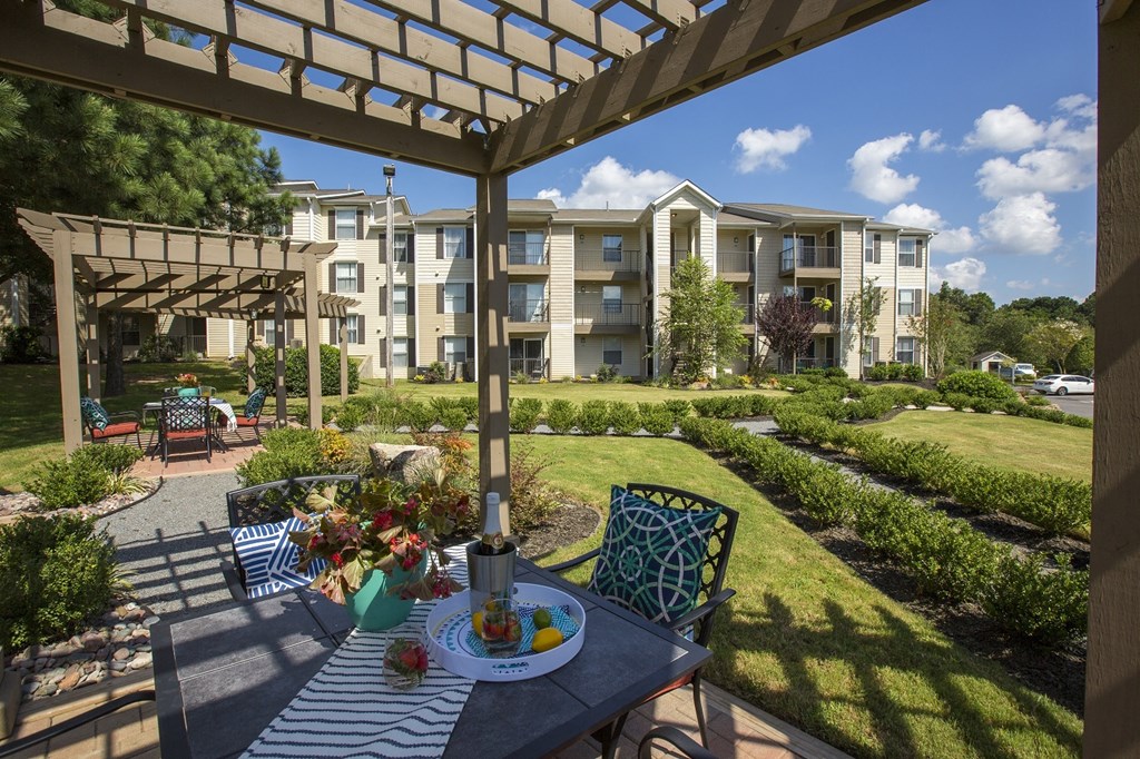 A patio with a table and chairs under a pergola.