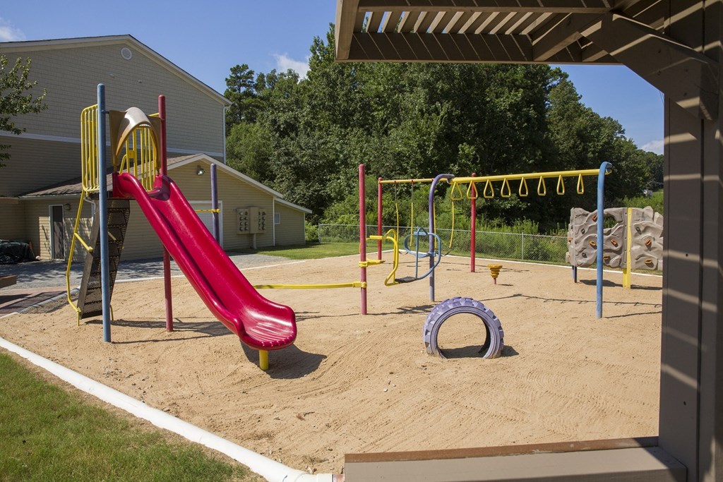 A playground with a red slide and a yellow and red climbing frame.