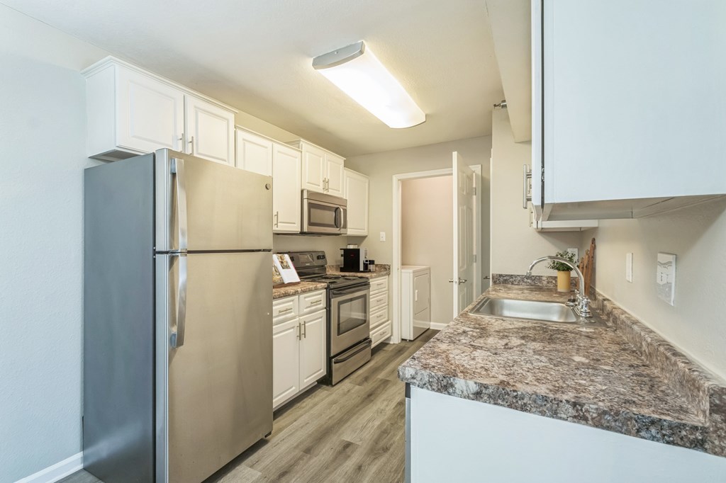 A kitchen with a granite countertop and stainless steel appliances.