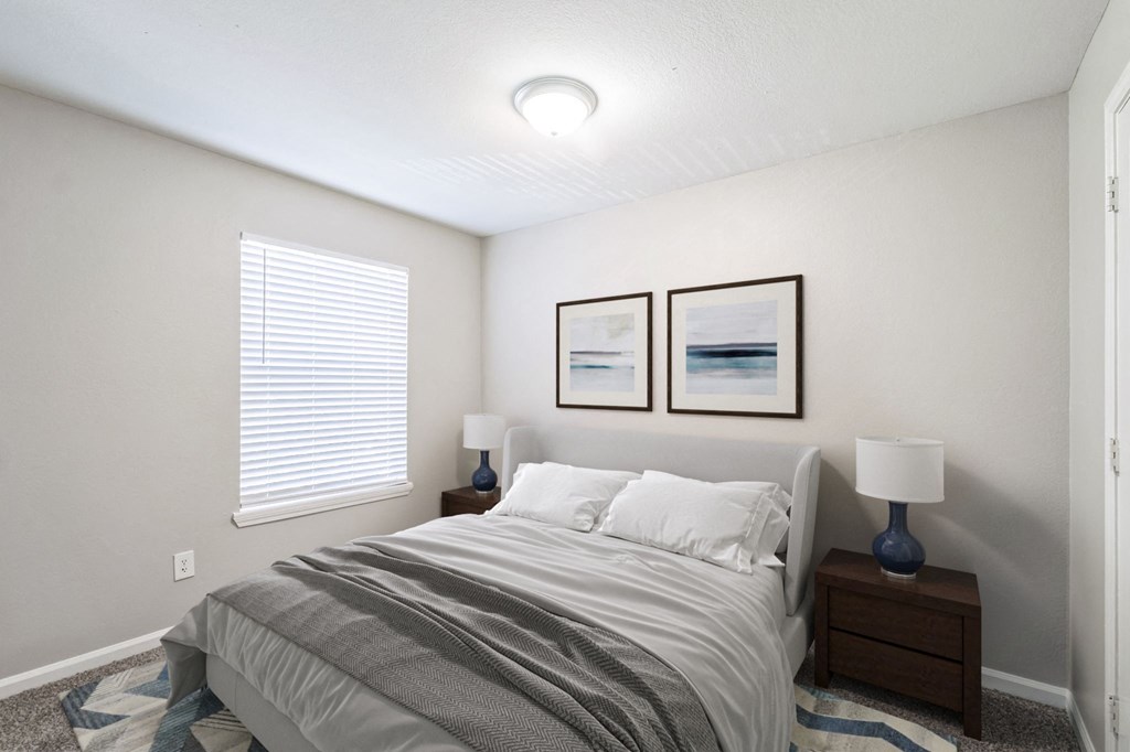 A bedroom with a bed, two lamps, and two pictures on the wall.