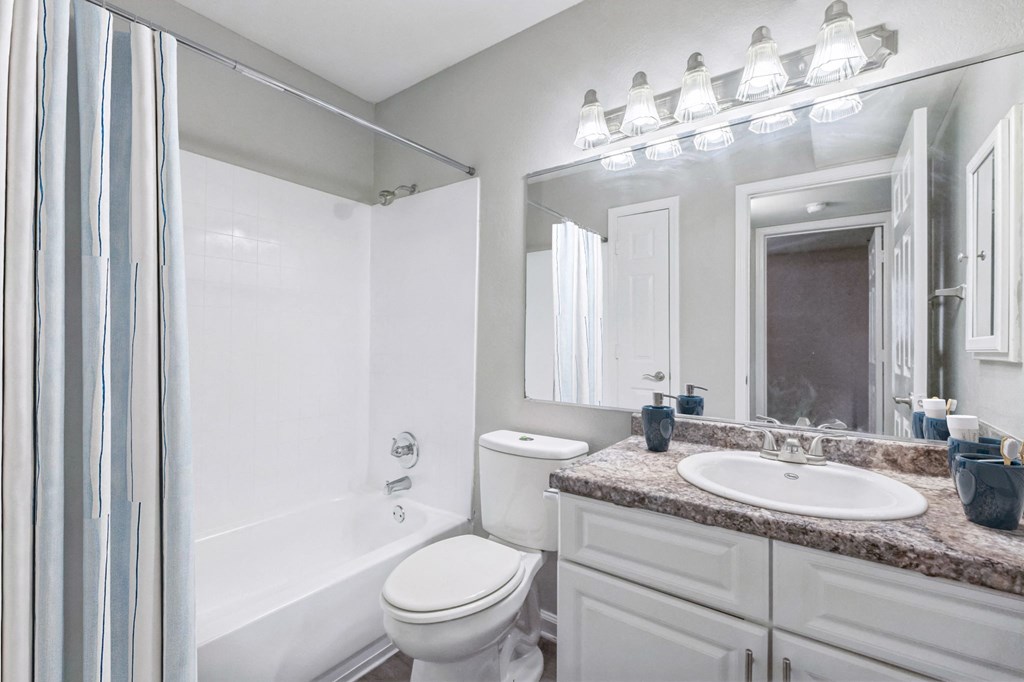 A white bathroom with a toilet, sink, and mirror.
