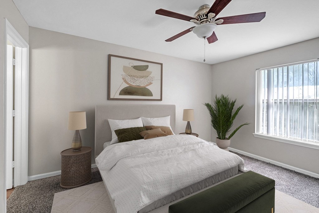 A bedroom with a large bed, a ceiling fan, and a painting on the wall.