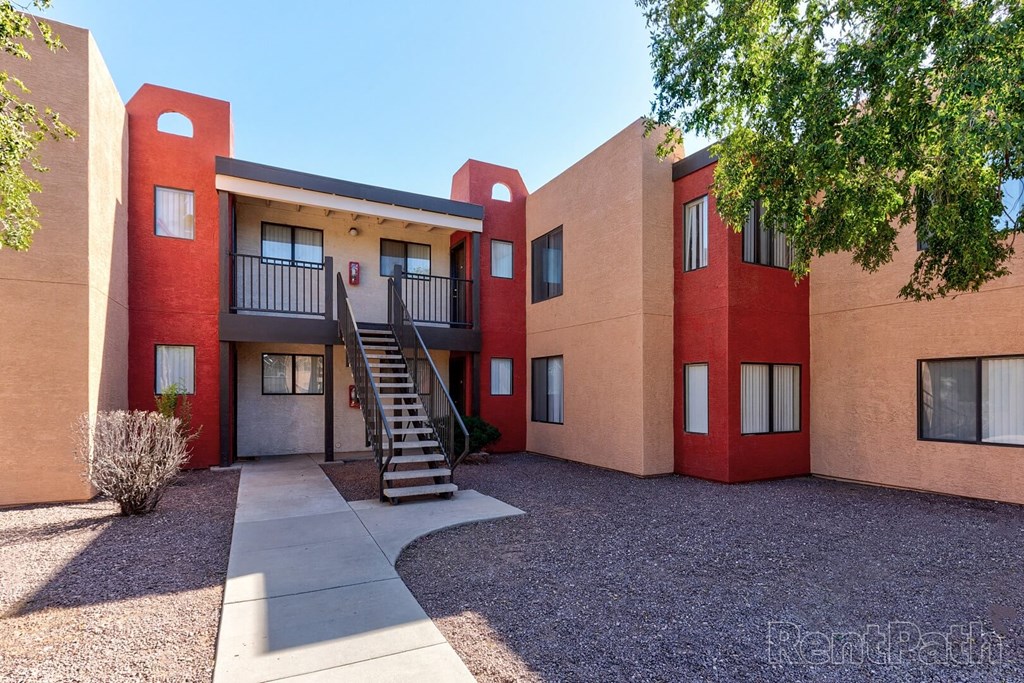 A red and beige building with a staircase leading to the entrance.