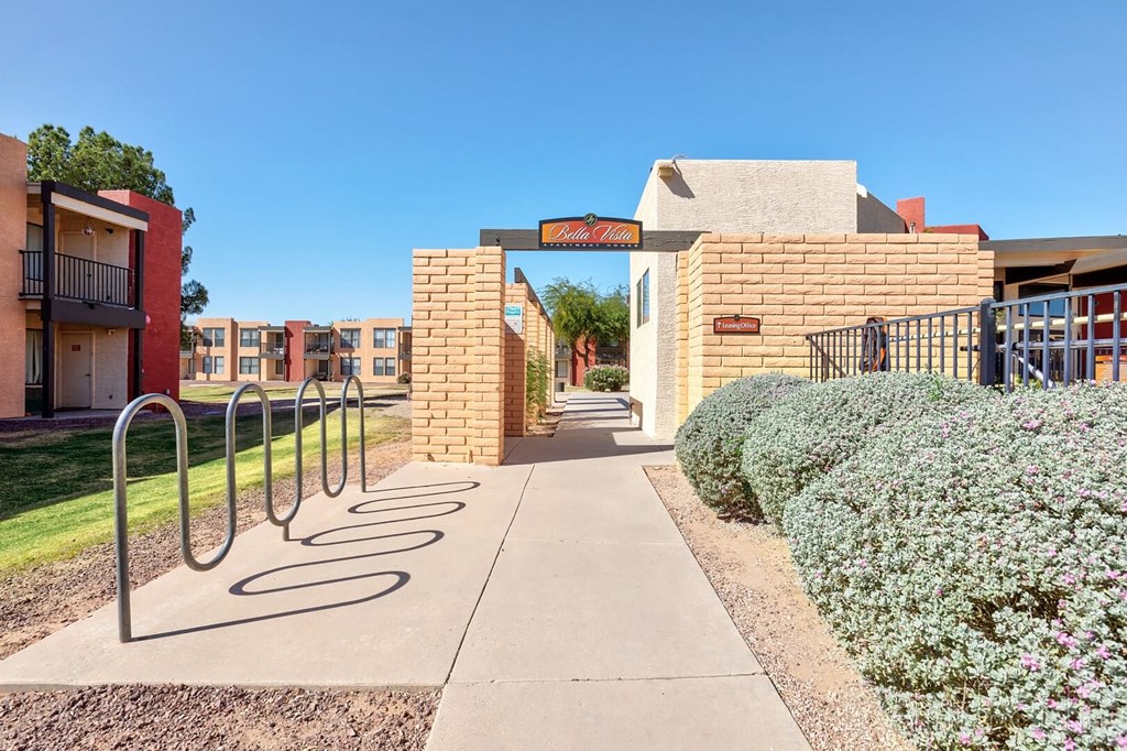 A pathway leads to a building entrance with a metal railing on the left.