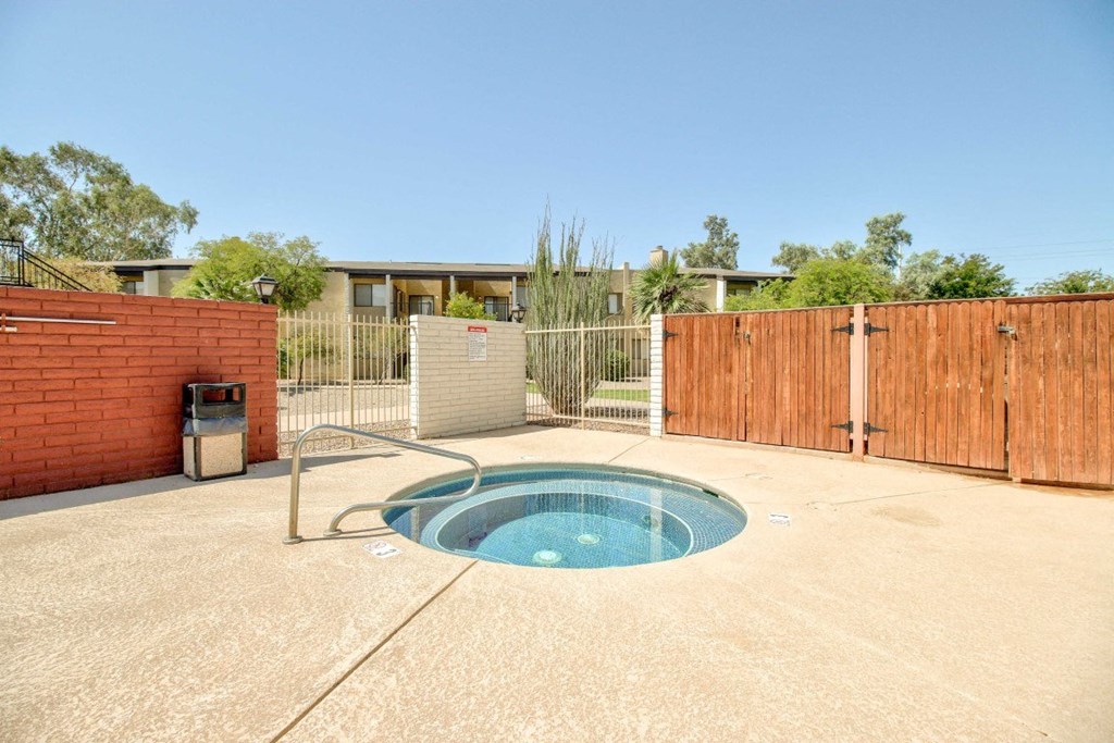 A small pool in a backyard with a fence and a house in the background.