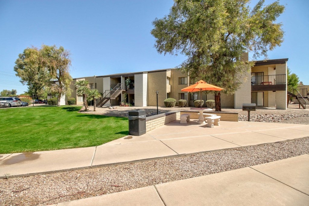 A modern building with a patio and a tree in front.
