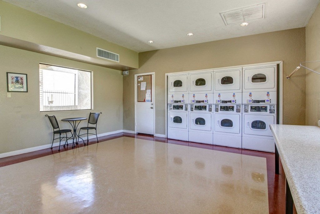 A kitchen with a table and chairs in the foreground and a laundry room in the background.