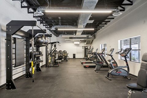 A gym with a variety of exercise equipment including treadmills, weights, and exercise bikes.