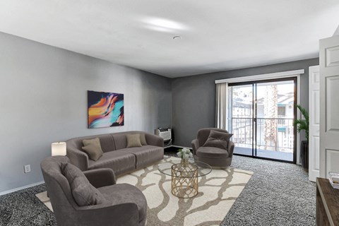 A living room with a grey couch, a brown armchair, and a painting on the wall.