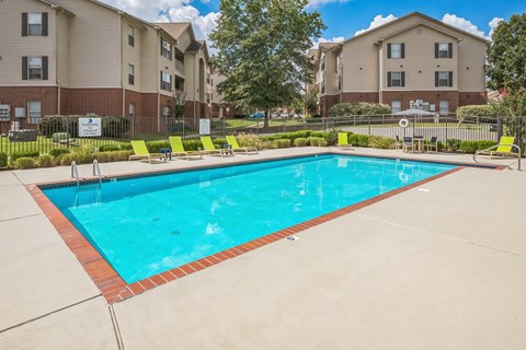 A swimming pool in a residential area with apartment buildings in the background.