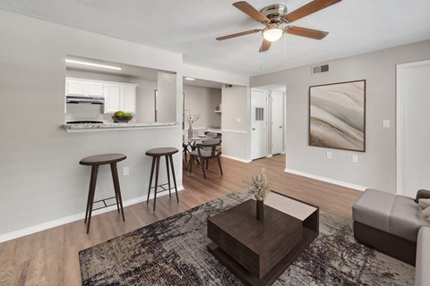 A living room with a ceiling fan and a rug on the floor.