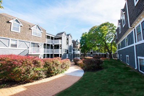 A pathway leads through a grassy area between two buildings.