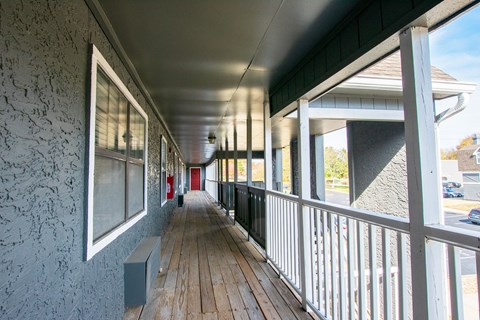 A long wooden porch with a white railing.