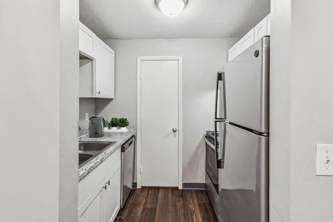 A kitchen with a refrigerator, sink, and cabinets.