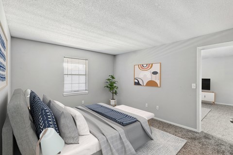 A bedroom with a bed, a couch, and a plant.