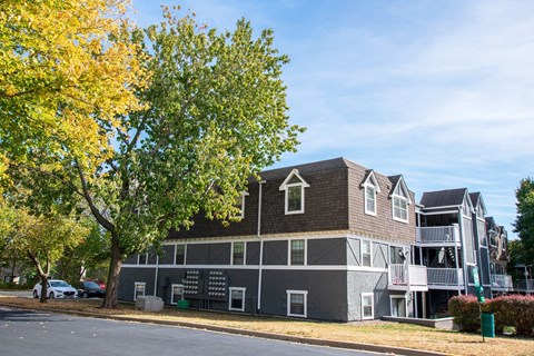 A large grey building with a tree in front of it.