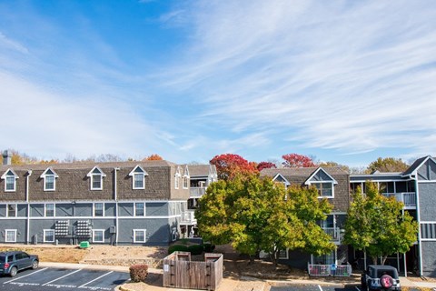 A parking lot in front of a building with trees.