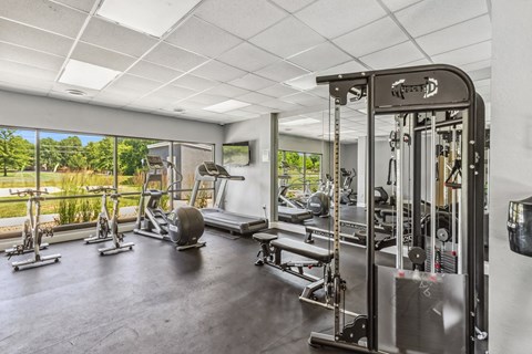 A gym with a variety of equipment including a weight bench, a leg press machine, and a cable machine.