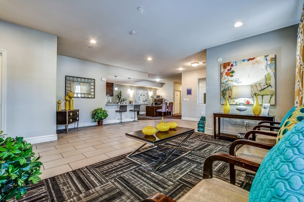 A living room with a rug, a yellow couch, and a painting on the wall.