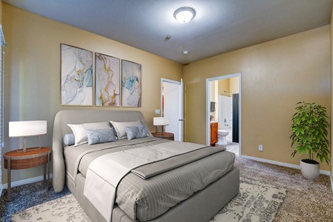A bedroom with a large bed, a lamp, and a plant.