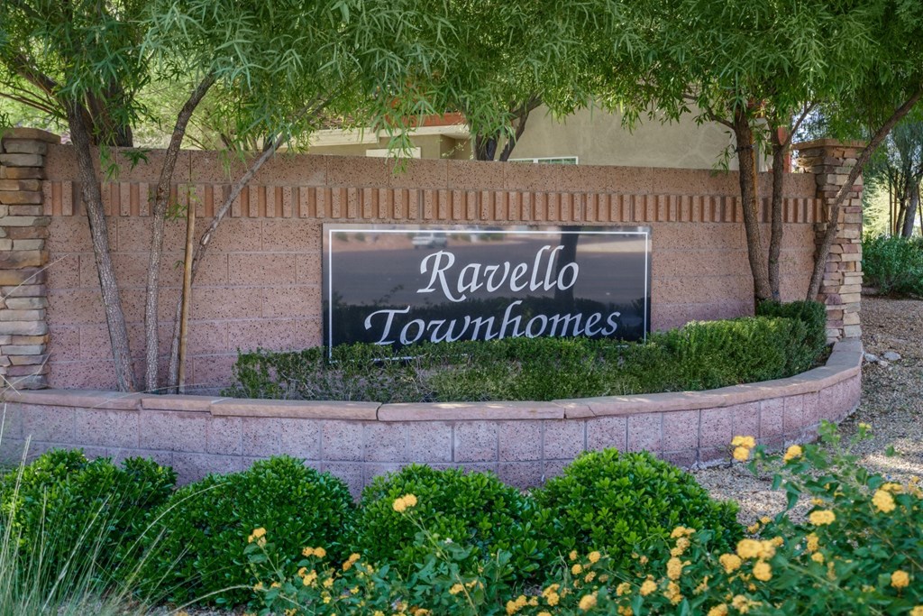 A sign that says Ravello Townhomes is surrounded by plants and trees.