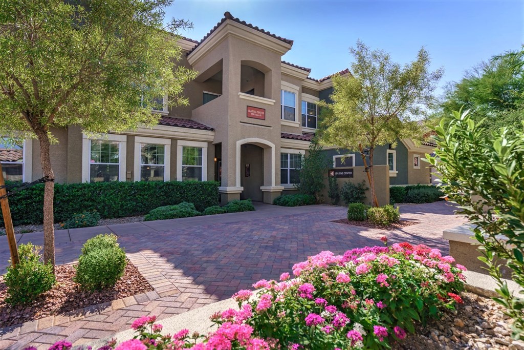 A house with a driveway and pink flowers in front.