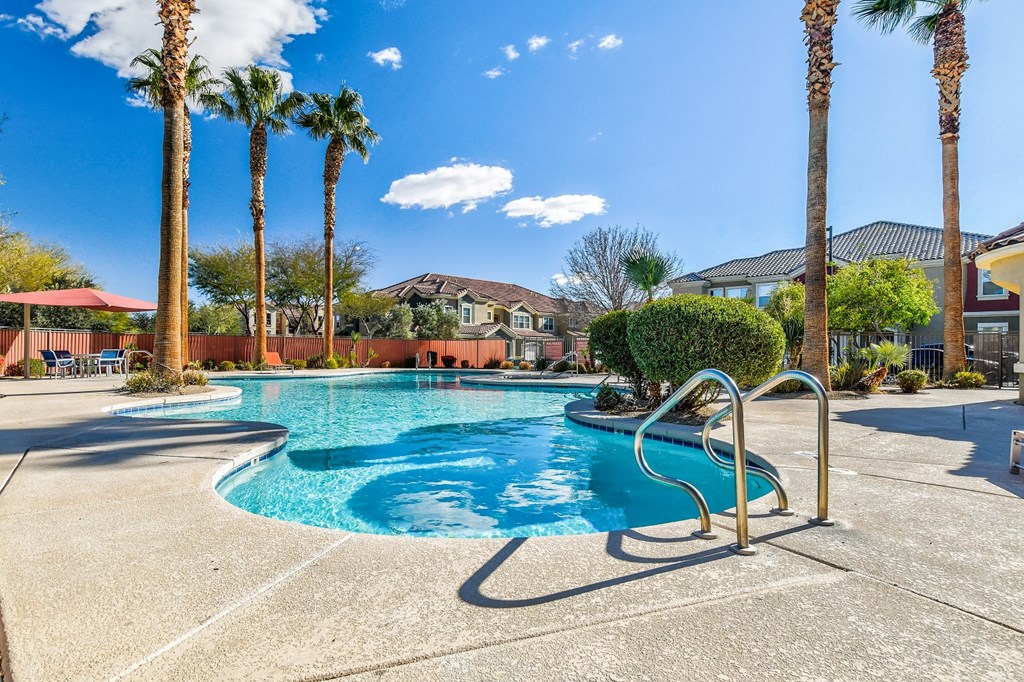 A pool surrounded by palm trees and a clear blue sky.