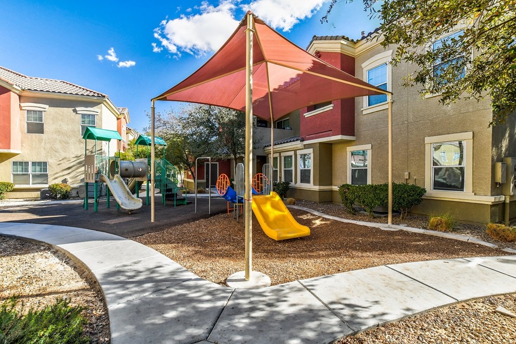 A playground with a red umbrella and a yellow slide.