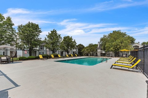 A large outdoor swimming pool surrounded by yellow sun loungers.