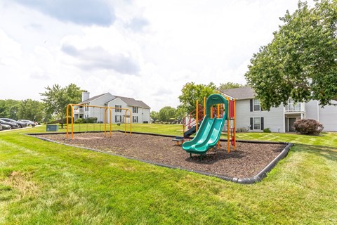 A playground with a green slide and a yellow swing set.