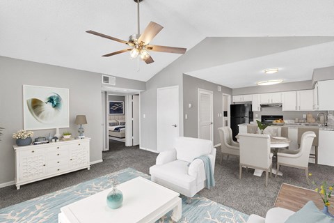 A living room with a ceiling fan and a dining area.
