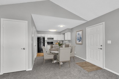A kitchen with a dining table and chairs is visible through an open door.
