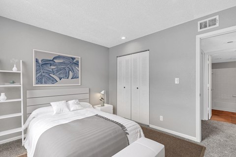 A bedroom with a large bed and a painting on the wall.