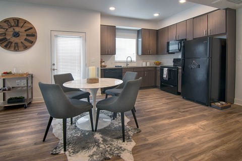 a kitchen with a black refrigerator and a table and chairs