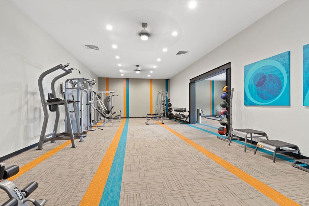 A gym with a variety of equipment including treadmills, weights, and exercise machines.