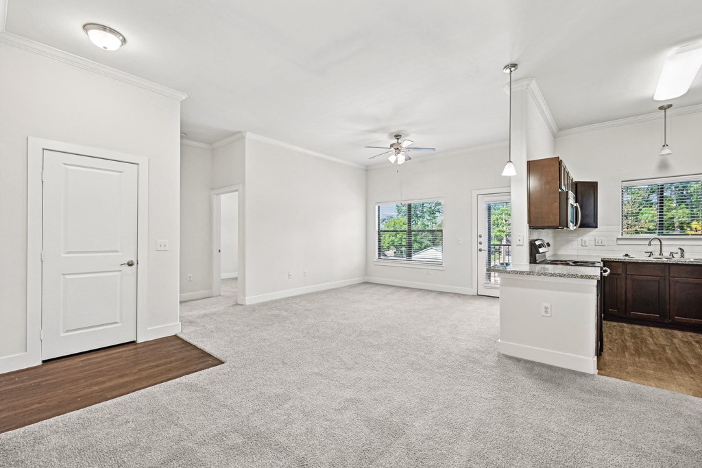 A spacious living room with a kitchen area in the background.