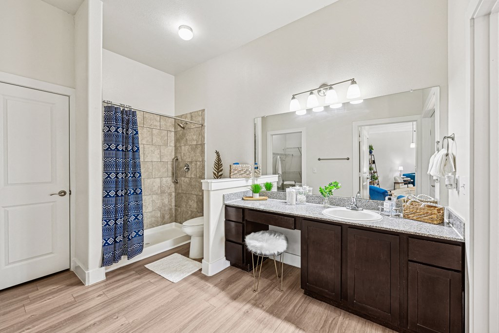A bathroom with a white door, a brown vanity, and a blue shower curtain.