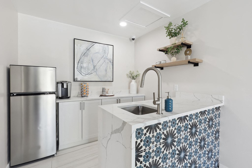 a kitchen with a marble counter top and a stainless steel refrigerator