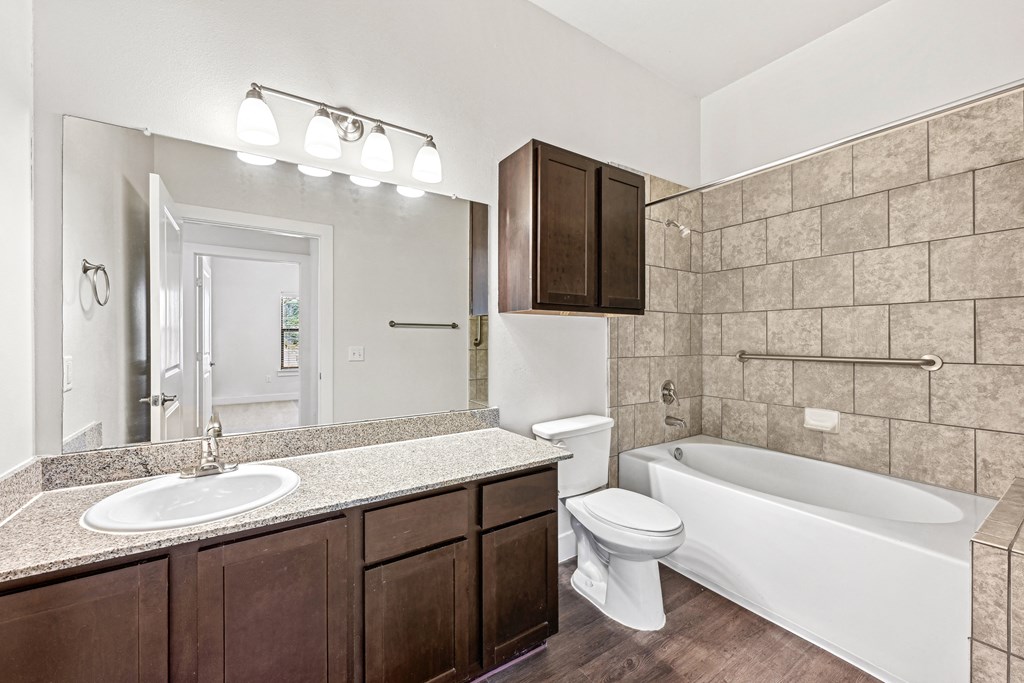 A bathroom with a white tub, sink, and toilet.