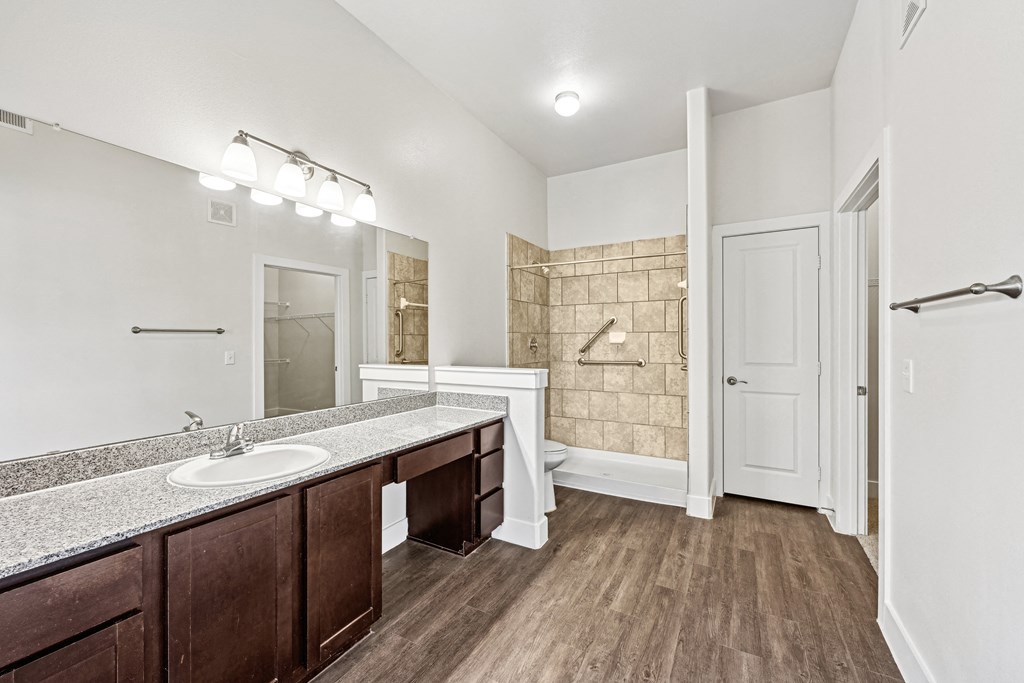 A bathroom with a sink, mirror, and wooden floors.