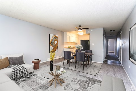 A modern living room with a dining area and a kitchen in the background.