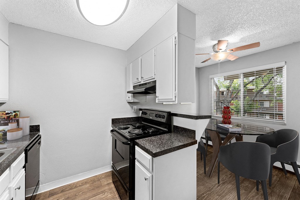 a kitchen with a stove and a dining room with a table and chairs