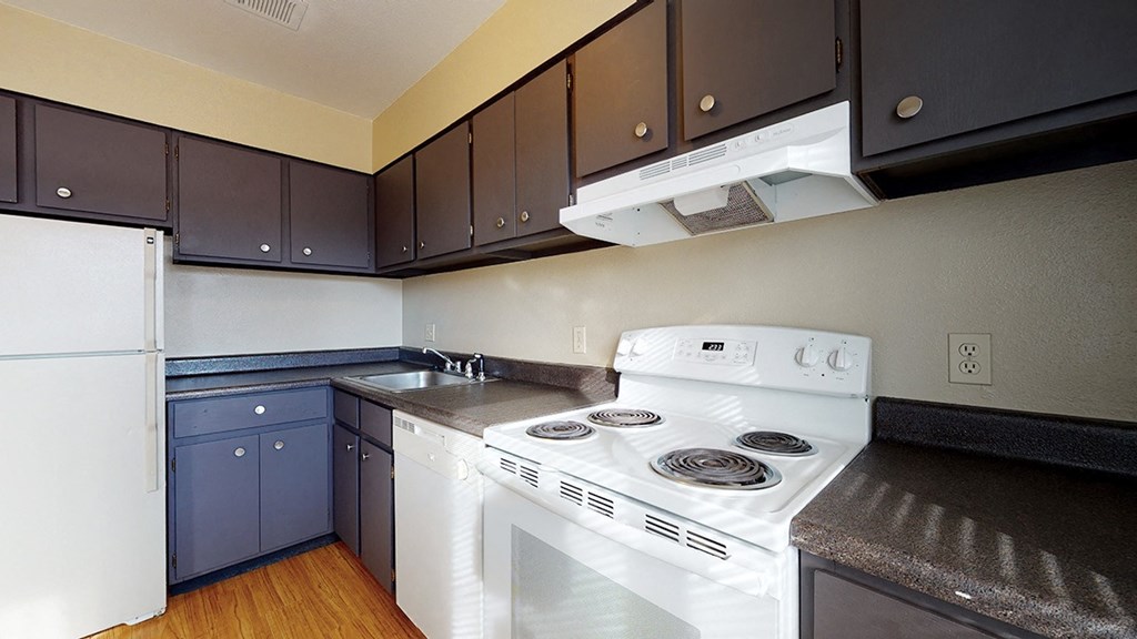 a kitchen with white appliances and dark cabinets