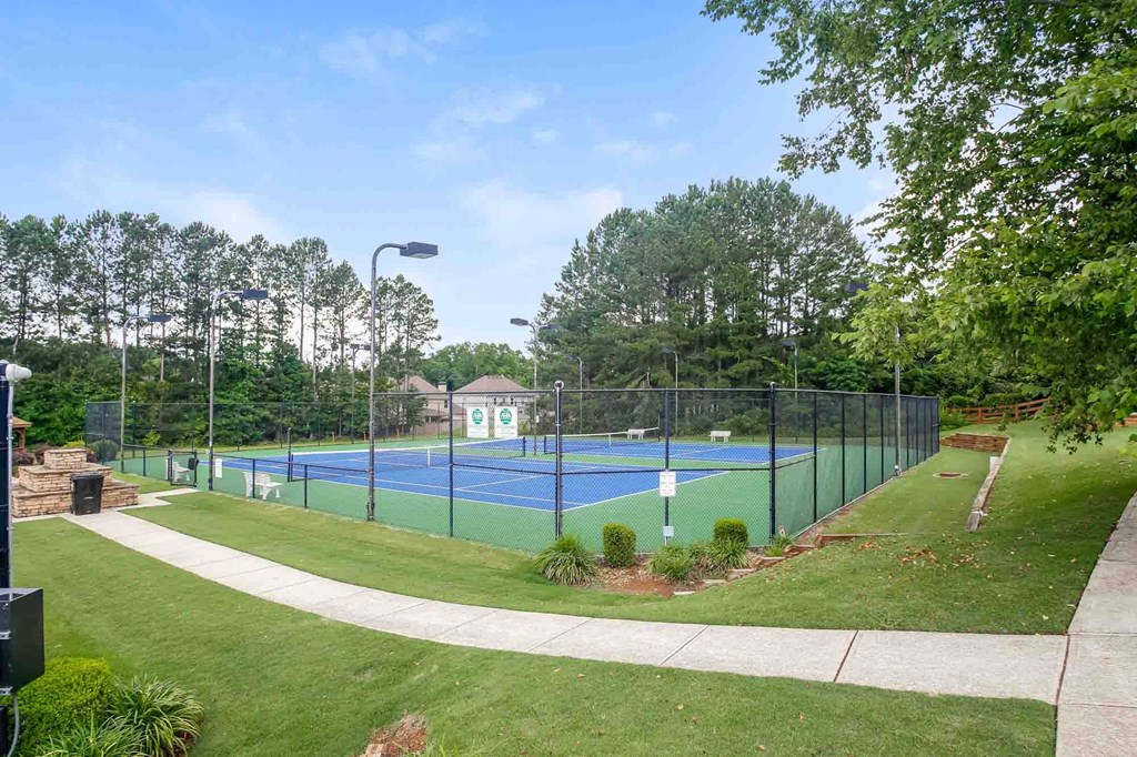 a tennis court with a fence around it in a park