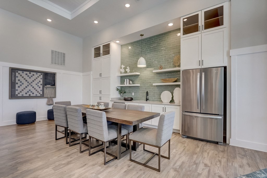 a dining room with a wooden table and chairs and a stainless steel refrigerator